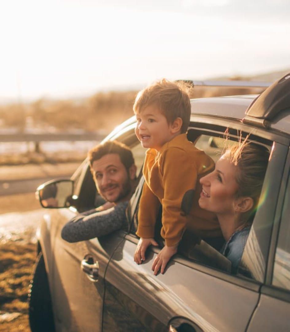 Mamma, papà e bambino guardano fuori dal finestrino di una macchina mentre posteggiata