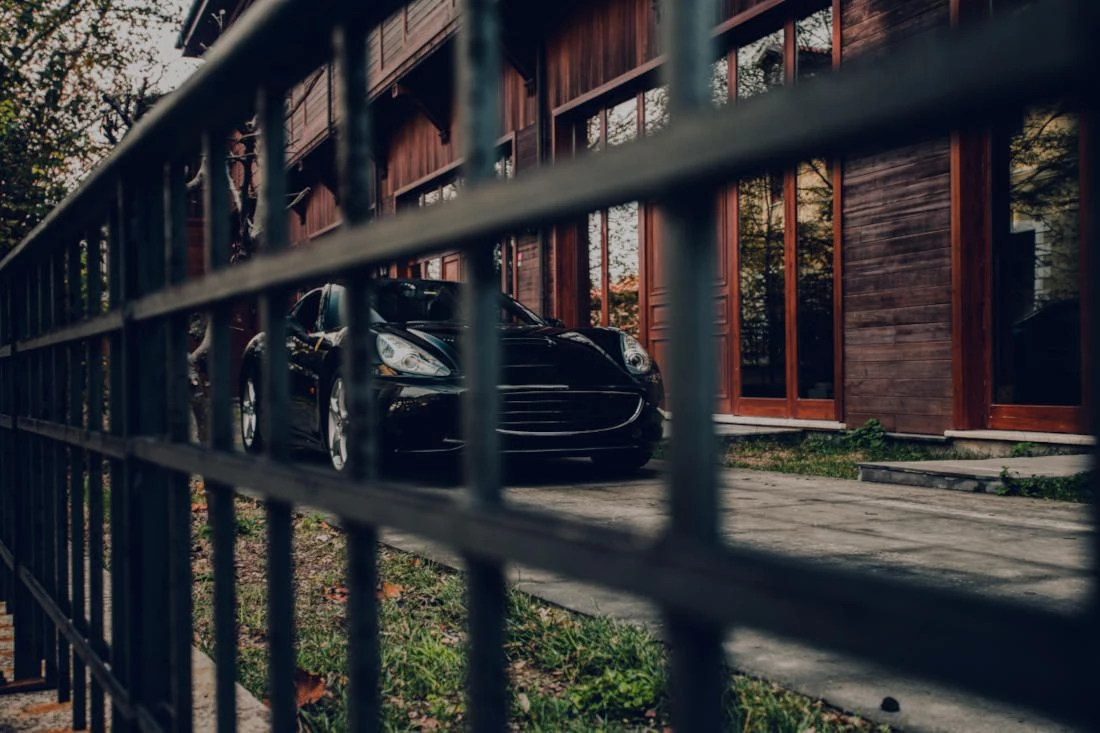 Macchina nera parcheggiata davanti a casa con vista di ringhiera nera