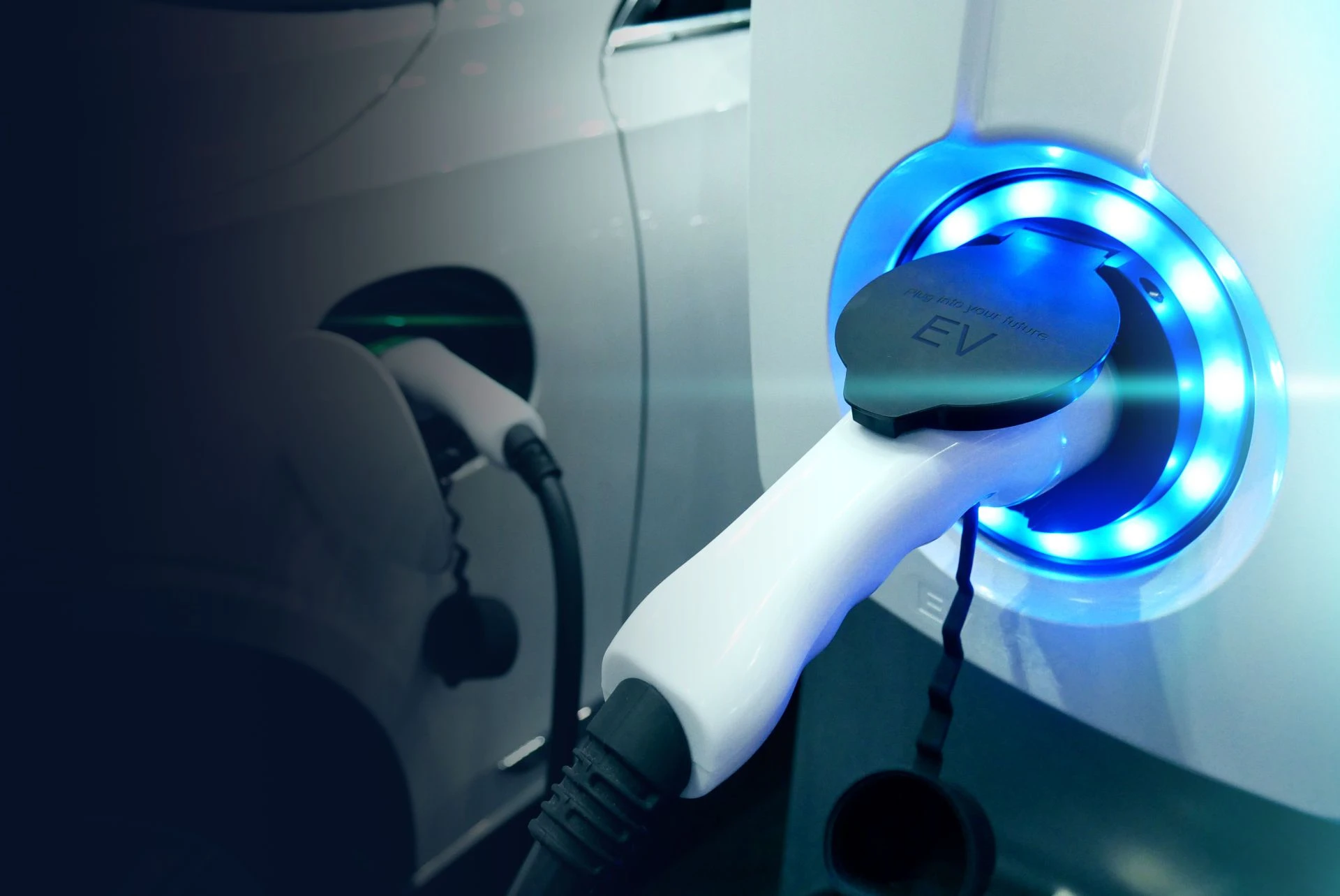 Cavo plug-in per veicolo elettrico nella presa di una colonnina di ricarica bianca 